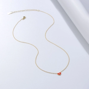 Détail du collier avec pendentif cœur rouge et petit zircon scintillant au centre de l'éclat