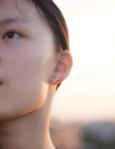 Close-up of S925 silver criss-cross X stud earring with gold finish and zircon stones
