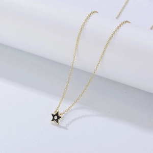 Détail d'un collier en chaîne dorée avec pendentif étoile noire et pierre en zircon