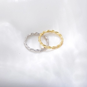 Detailed macro of gold and silver twisted rings with small diamonds and S925 stamp