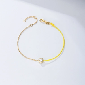 Close-up of heart-shaped zircon silver bracelet with yellow woven rope and 925 stamp