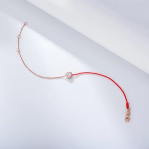 Macro shot of S925 silver heart zircon on a split red rope and rose gold chain bracelet