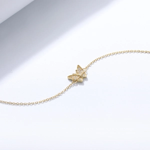 Macro shot of gold butterfly bracelet with sparkling cubic zirconia on a minimalist white background