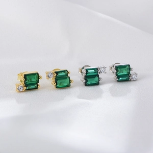 Detailed macro of geometric emerald zircon earrings in gold and silver plating