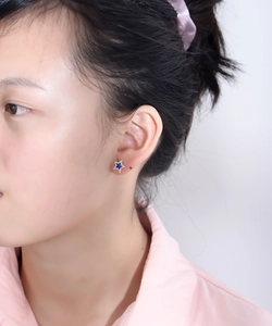 Close-up of model wearing s925 silver star stud earrings with blue enamel and gold glitter