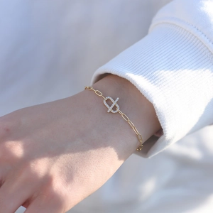 Detail of gold paperclip bracelet with zircon-encrusted geometric links on wrist