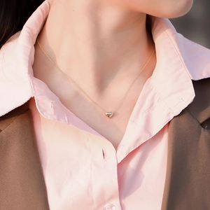 Close-up of a delicate hollow gold heart pendant necklace worn on a woman's collarbone