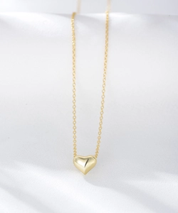 Detailed view of polished S925 sterling silver hollow heart pendant on a silk background