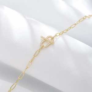 Macro shot of gold silver bracelet with a paved zircon oval link on white silk