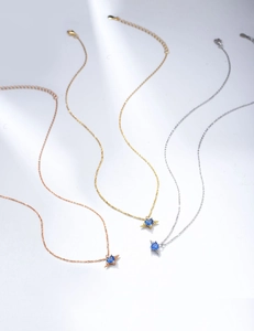 Detailed shot of three angel wing necklaces in rose gold, gold, and silver finishes