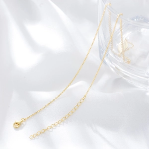 Detailed close-up of a 14K gold lobster clasp and adjustable link chain on satin