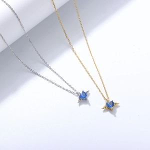 Close-up of heart-shaped blue gems and angel wing pendants in silver and gold