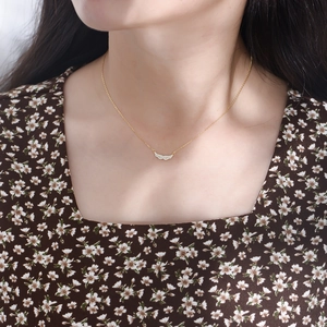 Close-up of gold angel wing pendant with pavé cubic zirconia on a delicate chain