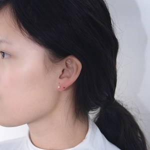 Gros plan d'une boucle d'oreille géométrique en argent avec cristal porté par un mannequin