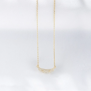Detailed close-up of golden angel wing pendant with micro-pave cubic zirconia on silk fabric