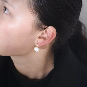 Detail of s925 silver vintage shell earrings with cubic zirconia on a model's ear