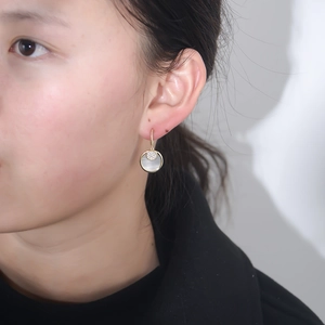 Eleganti orecchini dorati con pendente in madreperla e zirconi indossati da modella