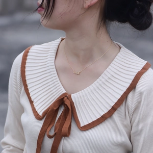 Gros plan d'un collier doré avec pendentif Wish en cursive sur le cou d'un mannequin