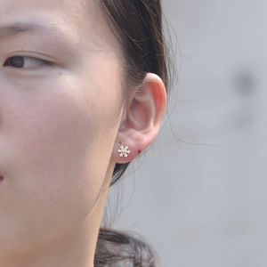 Close-up of a delicate gold snowflake stud earring featuring sparkling cubic zirconia stones
