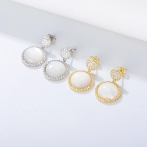 Close-up of S925 silver and gold earrings with white shells and pavé zircon details