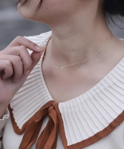 Gros plan d'un collier avec pendentif doré 'wish' sur le cou du mannequin
