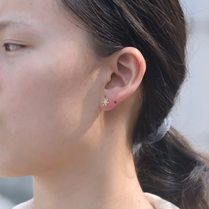 Detail of a golden bear stud earring inlaid with white zircon on a model's ear