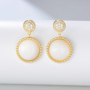 Close-up of golden S925 silver earrings with pavé zircon and white shell drop pendants