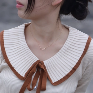 Collier minimaliste en or avec pendentif wish porté par un mannequin sur une tenue