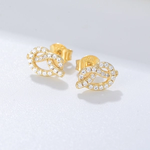 Macro detail of S925 sterling silver knotted earrings with gold plating and cubic zirconia