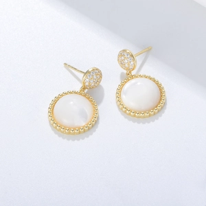 Macro detail of S925 silver shell earrings with gold beaded edges and pavé zircon stones