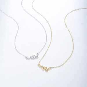 Colliers minimalistes argentés et dorés avec pendentif Wish sur fond gris clair