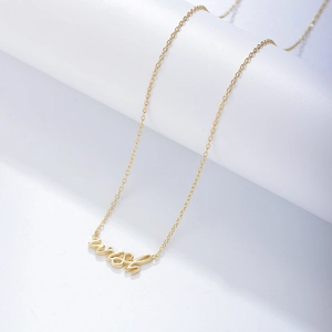 Gros plan d'un collier doré délicat avec un pendentif arborant le mot Wish élégant