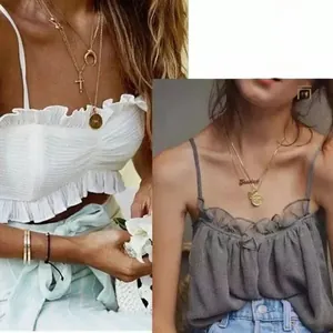 Detail of layered gold coin necklaces with cross and letter pendants on female models
