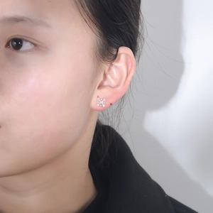 Close-up of snowflake stud earrings in rose gold with pink zircon worn by a model