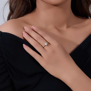 Detailed view of a six-prong classic gold ring with round moissanite on a finger