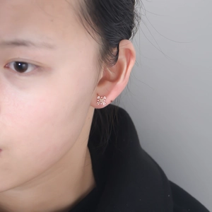 Close-up of pink and white zircon flower stud earrings on a model's earlobe