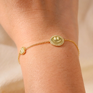 Bracelet doré avec pendentifs visage souriant et cœur orné de zircons étincelants