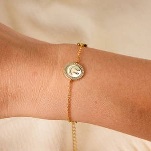 Gros plan d'un bracelet en or avec pendentif sourire en zircon sur le poignet d'une femme