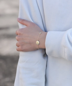 Détail d'un bracelet doré avec pendentifs smiley et cœur incrustés de zircons brillants