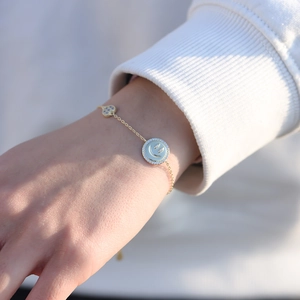 Gros plan d'un bracelet doré avec un visage souriant en zircon et un pendentif cœur