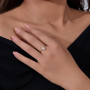 Detailed close-up of a pear-cut zircon ring in gold plating worn by a model