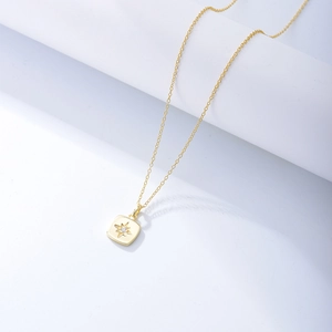 Detail of gold starburst square pendant necklace with a sparkling center zircon stone