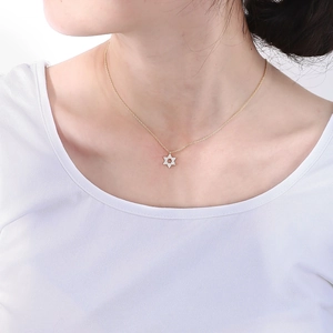 Close-up of a gold S925 silver hexagram pendant with pavé zircon stones on a female model