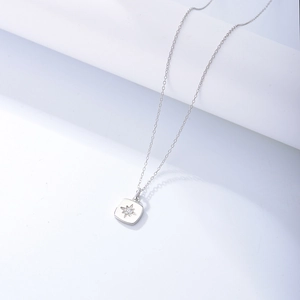 Sterling silver necklace with minimalist starburst zircon square pendant on white prop