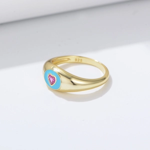 Gros plan du poinçon 925 sur bague en or avec pierre cœur rose et émail bleu