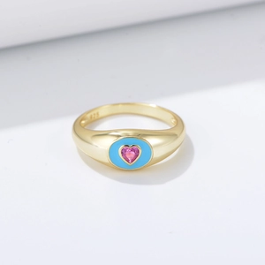 Détail d'une pierre rose en cœur sur bague en argent 925 doré avec émail bleu ciel
