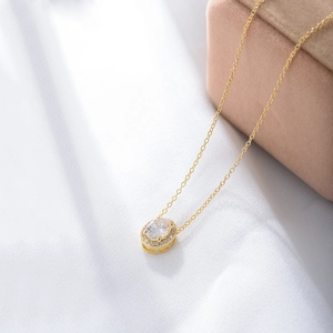 Macro shot of oval halo pendant necklace with pavé stones on silky white fabric