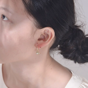 Detailed view of gold shell drop earrings with white pearl and pave zircon stones