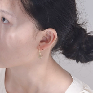 Close-up of elegant gold fishbone drop earrings with sparkling crystals worn by a model