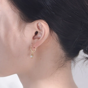Detail of s925 silver shell pearl earring worn on ear with gold leaf charm